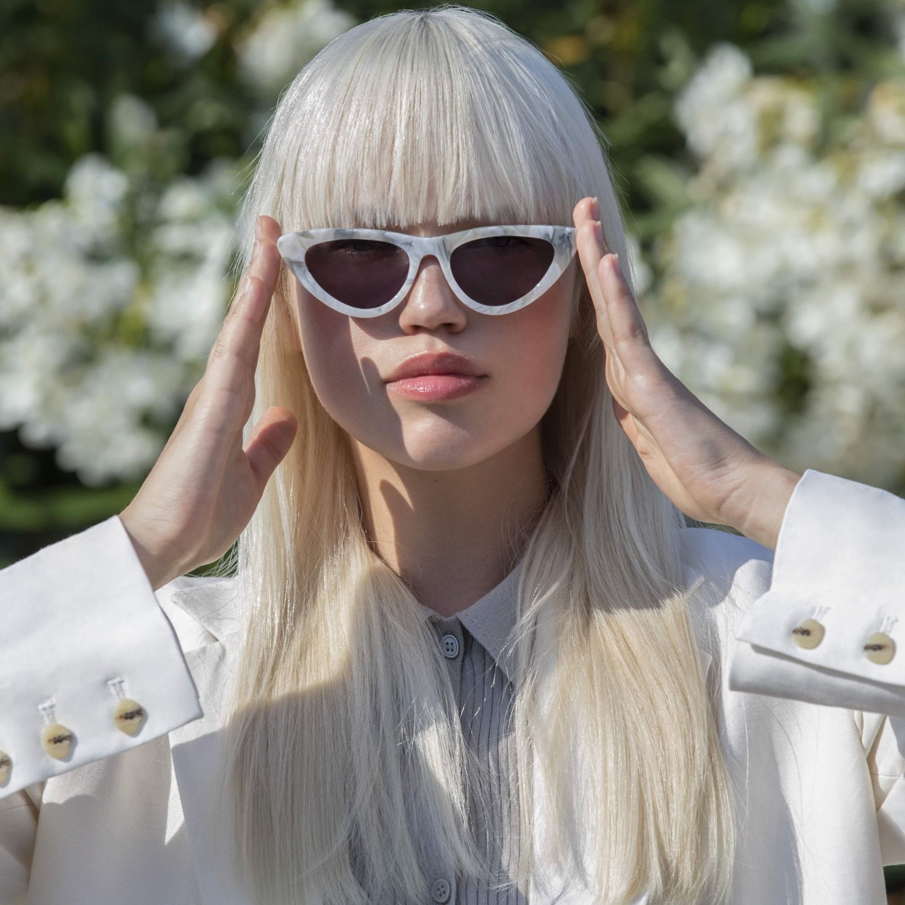 a woman wearing sunglasses is sitting on a bench 