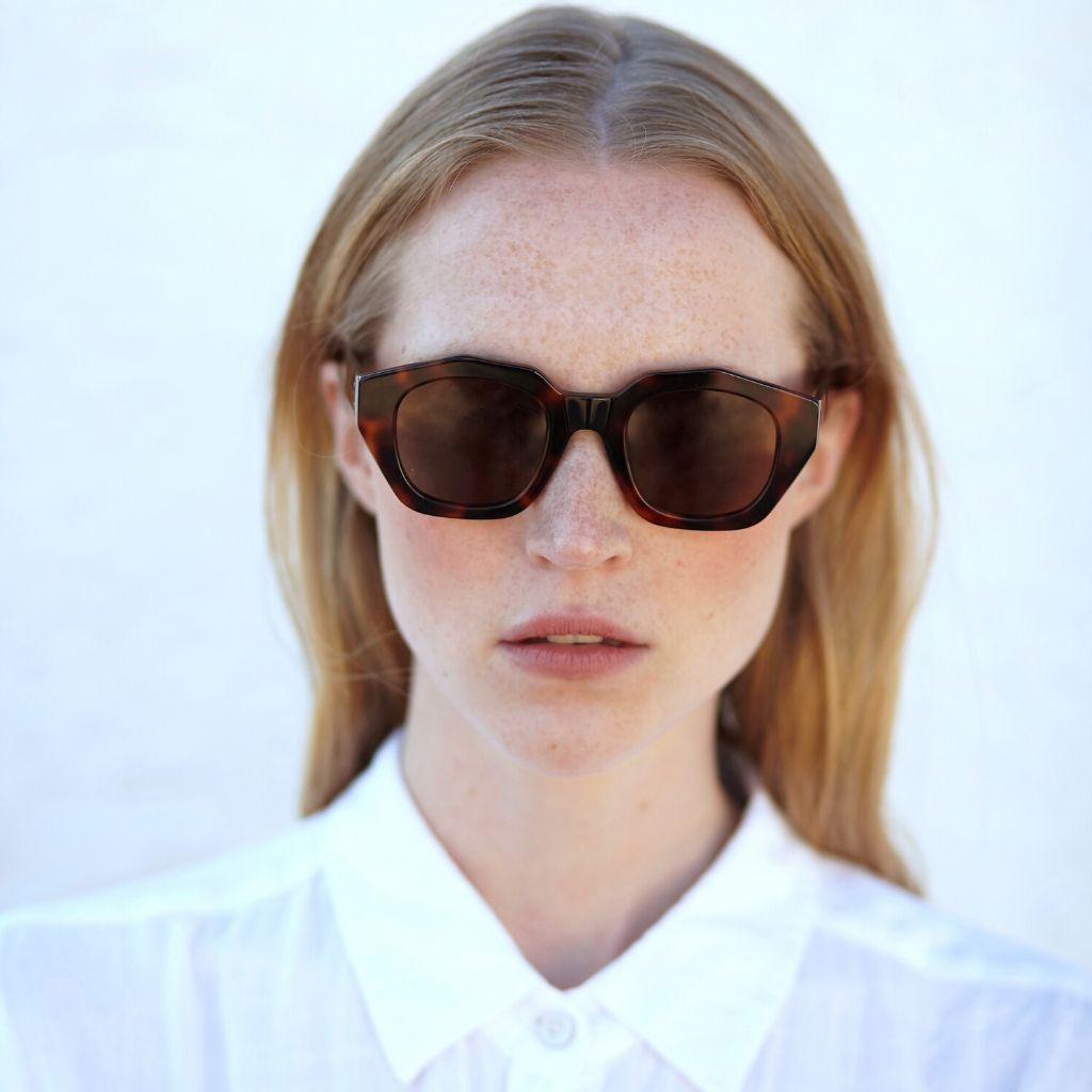 a woman wearing sunglasses and a white shirt 