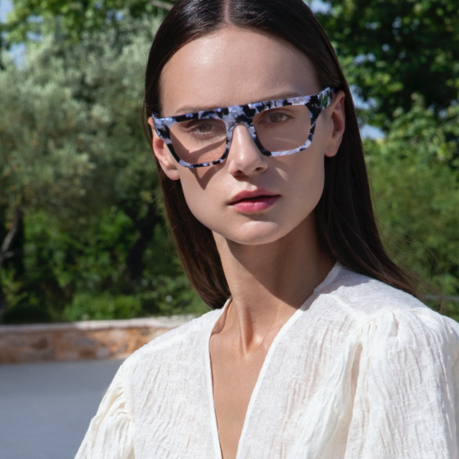 a woman wearing sunglasses and a white dress 