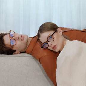 a woman laying down on a bed with glasses 